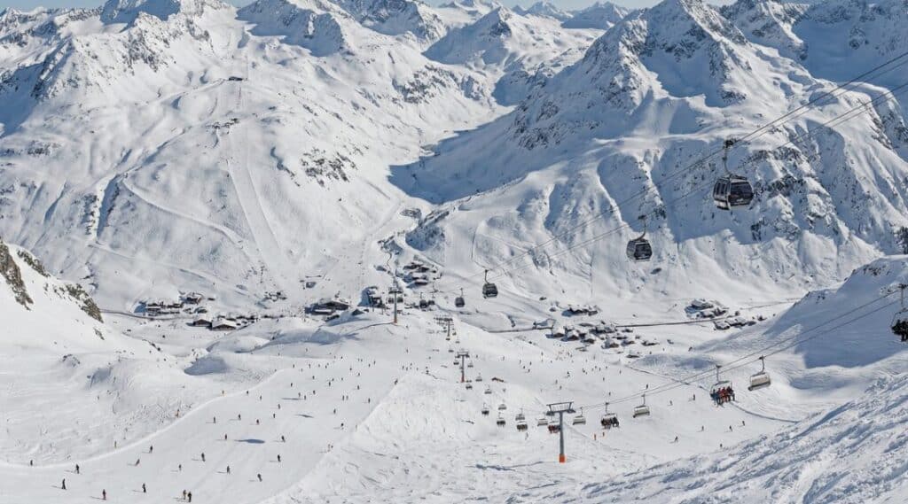 Aerial view of the vast Arlberg ski area with gondolas, chairlifts and hundreds of skiers across 305 km of total ski runs.