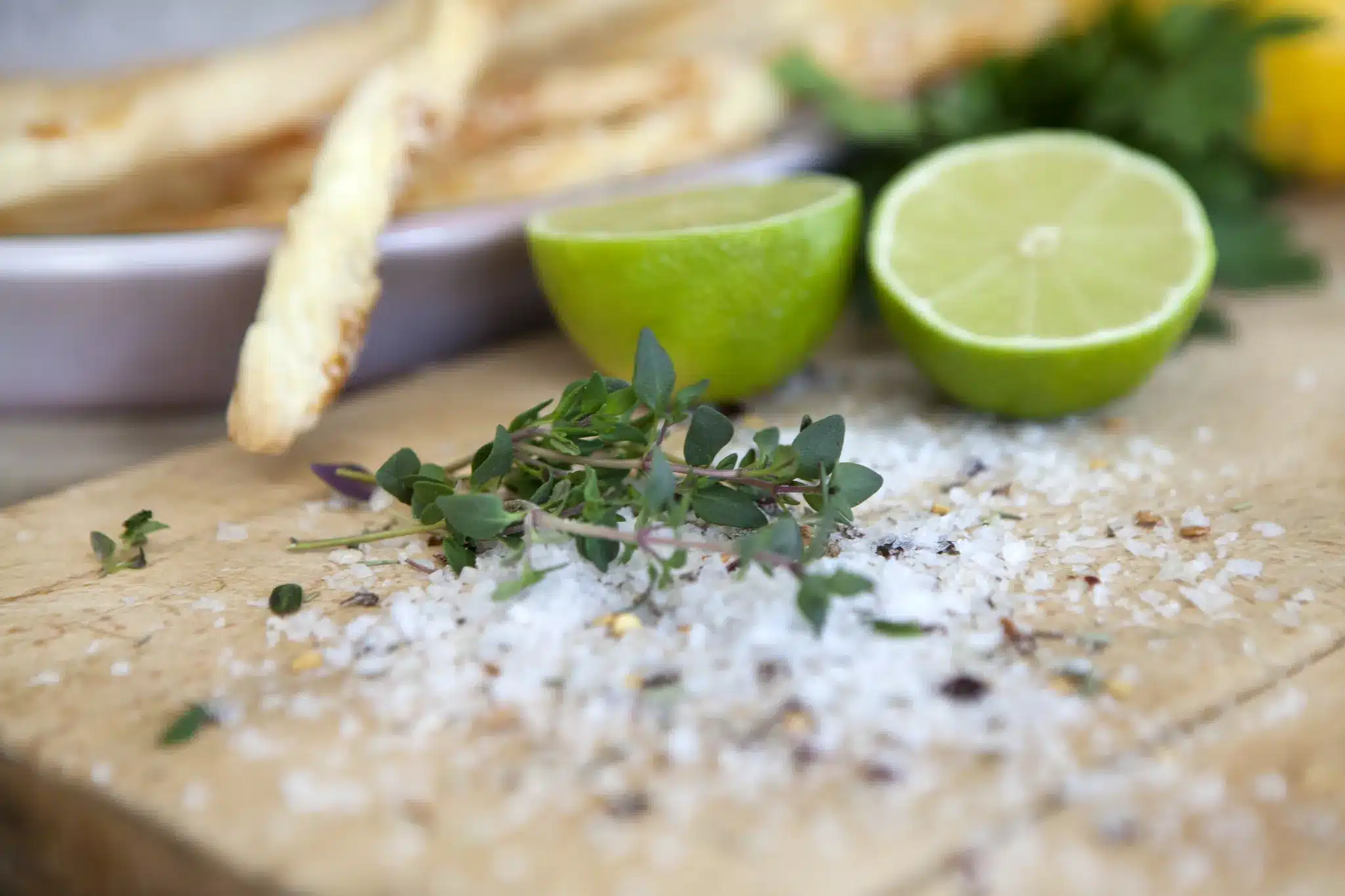 Startseite 69 Breadsticks, lime and herbs with sea salt on a wooden board