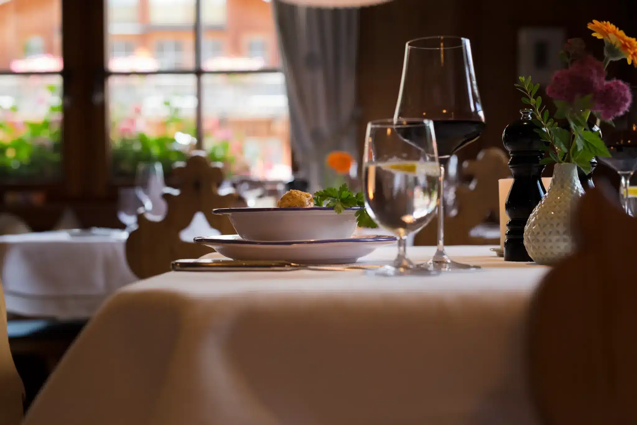 Startseite 128 Set table with a wine glass and flowers by the window in the restaurant